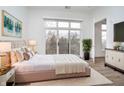 A luxurious main bedroom with large window, balcony access, and plush, neutral-toned bedding on top of a white rug at 15 W Executive Dr # 104, Carmel, IN 46032