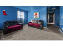 Vibrant blue living room featuring comfortable black sofas, soft carpeting, and bright natural light from the window at 2610 Caroline Ave, Indianapolis, IN 46218