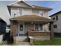 Two-story home with a covered front porch, brick pillars, and neutral siding at 304 N Hackley St, Muncie, IN 47305