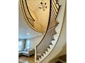Elegant curving staircase with dark wrought iron balusters and views of the living area at 307 S Main St, Whitestown, IN 46075