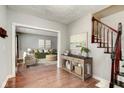 A foyer featuring hardwood floors, a staircase, and a view into the staged living room at 49 N Tremont St, Indianapolis, IN 46222