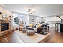 Open-concept living space with a stone fireplace, a ceiling fan, and hardwood floors with an open view to the kitchen at 6848 Kara Ln, Brownsburg, IN 46112