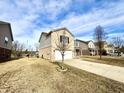 A tan and brick home with a two car garage, concrete drive and trees in the front yard at 11852 Geyser Ct, Fishers, IN 46038