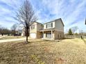 A lovely tan and brick two story home with a covered front porch and two car garage at 11852 Geyser Ct, Fishers, IN 46038