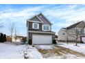 Attractive two-story home with a gray and stone front, showcasing a two-car garage and winter landscaping at 19462 Chip Shot Rd, Noblesville, IN 46062