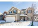 Attractive two-story home featuring brick and vinyl siding, complemented by a well-manicured front yard in winter at 5303 Brandywine Dr, Whitestown, IN 46075