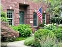 Inviting brick home featuring a well-manicured front yard, lush greenery, and an American flag at 6045 Channel Dr, Columbus, IN 47201
