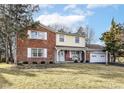 Charming two-story home featuring a brick facade, yellow siding, and a well-maintained front yard at 6838 Johnson Rd, Indianapolis, IN 46220