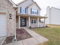 Close-up of the home's facade featuring a covered front porch, brick accents, and classic design elements at 7625 Corsican Cir, Avon, IN 46123