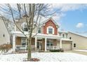 Charming two-story home with a welcoming front porch, and attached two car garage in winter at 13685 Van Buren Pl, Fishers, IN 46038