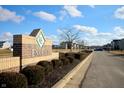 Well-maintained community entrance with brick signage and manicured landscaping on a sunny day with blue sky at 13858 N Zenas Ct, Camby, IN 46113