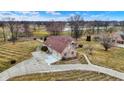 Aerial view of estate home with a three-car garage and a long driveway in mature wooded community at 2566 E Fairway Village Dr, Greenfield, IN 46140