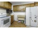 Functional kitchen with wood cabinets, a white refrigerator, and essential appliances for meal preparation at 3807 S Olney St, Indianapolis, IN 46237