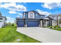 Stylish two-story home with a three car garage, blue siding, stone accents, and manicured green lawn at 5461 Oak Knoll Dr, Whitestown, IN 46075