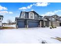 Charming two-story house featuring a three-car garage and welcoming front porch in a snowy landscape at 5461 Oak Knoll Dr, Whitestown, IN 46075