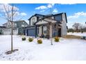 Inviting two-story home showcasing a three-car garage and an charming front porch in a snowy neighborhood at 5461 Oak Knoll Dr, Whitestown, IN 46075
