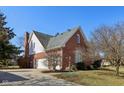 Brick home featuring a side entry garage, lush greenery, and well-maintained landscaping at 7238 River Birch Ln, Indianapolis, IN 46236
