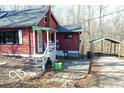 Red home with a welcoming front porch and a carport, all nestled on a wooded lot at 9464 N State Rd 135, Morgantown, IN 46160