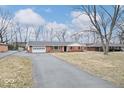 Charming brick ranch-style home with an attached garage and a long driveway at 1313 Oakwood Trl, Indianapolis, IN 46260