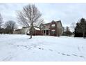 Side view of a brick home with a partially covered porch surrounded by a snow covered yard at 14596 Toponas Pl, Fishers, IN 46040