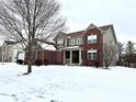Side view of a brick home with a partially covered porch and snow in the yard at 14596 Toponas Pl, Fishers, IN 46040