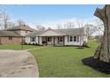 Inviting single story home showcasing a lush front lawn, mature trees, and a welcoming front porch with swing at 2109 Elmwood Dr, Lebanon, IN 46052