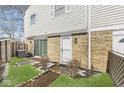 Exterior view of the townhome with brick facade, white door, sliding glass door and a small fenced yard at 3986 Braddock Rd, Indianapolis, IN 46268