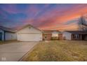 Charming single-story home featuring vinyl siding, attached garage, and landscaped front yard against a colorful sunset sky at 5347 Rolling River Ct, Indianapolis, IN 46221