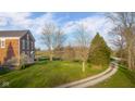 Expansive backyard of a brick home showcasing a lush lawn, mature trees, and rolling hills at 5752 River Rd, Waldron, IN 46182