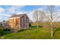 Brick home with a manicured lawn featuring mature trees, a gazebo, and a white porch swing at 5752 River Rd, Waldron, IN 46182