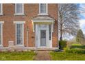 Inviting front entry of a brick home featuring a decorative portico, sidelights, and brick pathway at 5752 River Rd, Waldron, IN 46182