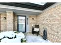 Inviting front entryway with brick accents, decorative chair with pillow and a gray front door at 9247 Backwater Dr, Indianapolis, IN 46250