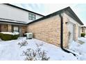 Townhome exterior featuring brick accents, neutral siding, attached garage, landscaping and snow-covered yard at 9247 Backwater Dr, Indianapolis, IN 46250
