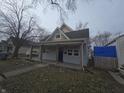 Traditional one-story home with front porch, gray siding and mature trees at 952 N Concord St, Indianapolis, IN 46222