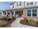 Inviting front porch featuring brick columns, a wreath on the front door, and landscaped flower beds at 11856 Springtide Ln, Fishers, IN 46037