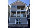 Three-story home featuring covered balconies on the upper two floors and a grey exterior with white trim at 15405 Mystic Rock Dr, Carmel, IN 46033