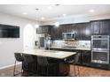 Modern kitchen featuring an island with seating, stainless appliances, and dark wood cabinetry at 1566 Dorset Dr, Avon, IN 46123