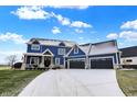 Beautiful blue home showcasing a spacious driveway and well-maintained front lawn at 20451 Chatham Hills Blvd, Westfield, IN 46074