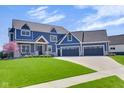 Charming two-story home with blue siding, stone accents, and a three-car garage at 20451 Chatham Hills Blvd, Westfield, IN 46074