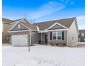 Attractive exterior of a home with gray siding, a brick facade, and a two-car garage amidst a snowy landscape at 293 Carrick Glen Blvd, Pendleton, IN 46064
