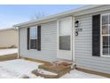 Grey siding with black shutters, the front door is white with a glass screen door and house number at 3331 Fall Valley Dr, Columbus, IN 47203