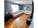 Bright living room featuring hardwood floors, a large sectional sofa, and a wall of picture frames at 739 Quarterhorse Run, Bargersville, IN 46106