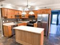 Well-equipped kitchen featuring an island, stainless steel refrigerator, oak cabinets and mosaic tile backsplash at 7824 Inverness Dr, Indianapolis, IN 46237
