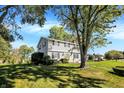 Two-story home with light gray siding, a well-manicured lawn, and a tree-lined yard at 908 Whispering Trl, Greenfield, IN 46140