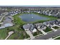 Expansive aerial view of a grey home nestled in a community near a scenic pond at 10297 Anees Ln, Fishers, IN 46040