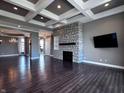 Spacious living room with a stone fireplace, coffered ceiling, and dark hardwood floors at 10297 Anees Ln, Fishers, IN 46040