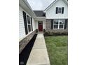 Inviting front entrance with a red door, stone accents, black shutters, and well-kept landscaping at 1202 Brightwood Cir, Greenfield, IN 46140