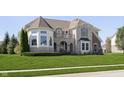 Charming stone and brick home featuring a turret, arched entryway, and a large lawn with established landscaping at 3236 Willow Bend Trl, Zionsville, IN 46077