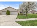 Beautiful single-story brick home boasts a lush front lawn, two-car garage, mature trees, and charming curb appeal at 4038 Oak Trail Dr, Indianapolis, IN 46237