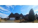 Attractive brick home featuring a two car garage, manicured lawn, and beautiful blue skies on a sunny day at 6641 Stone Pointe Way, Indianapolis, IN 46237